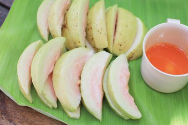 Taze guava ve muz yaprağına batırılmış tatlı sosla dilimlenmiş. Tropikal, aşçı ve sağlıklı yaşam tarzı..