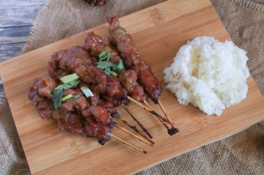 Izgara domuz şişi ya da ahşap kesme tahtasındaki yapışkan pirinçle yapılan pinpon yemeği. Popüler Tayland sokak yemekleri.