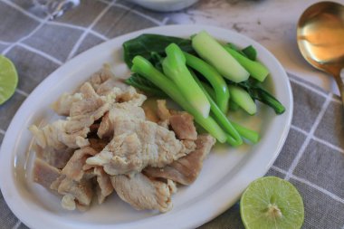 Boiled Pork with Lime Garlic, kale and Chili Sauce in white plate. Thai hot and spicy food. Healthy eating, Asian cuisine, and sustainable dining. clipart