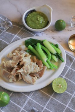 Boiled Pork with Lime Garlic, kale and Chili Sauce in white plate. Thai hot and spicy food. Healthy eating, Asian cuisine, and sustainable dining. clipart