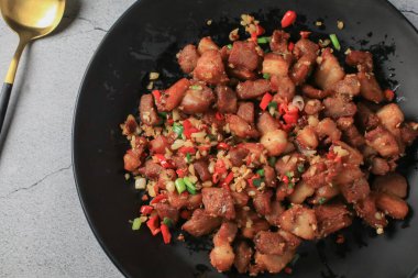 Kırmızı biberle pişirilmiş domuz eti ve siyah tabakta pirinçli sarımsak. Asya yerel sokak yemekleri tarzı.