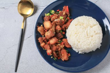 Kırmızı biberle pişirilmiş domuz eti ve siyah tabakta pirinçli sarımsak. Asya yerel sokak yemekleri tarzı.