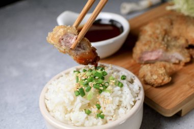 Elle yemek çubuğu, Japon usulü kızarmış domuz pirzolası, tatlı ekşi sos ve ahşap karının üstünde pirinç tarifi yiyor. Asya yemekleri.