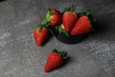 Koyu arkaplanda taze çilekler. Yazın kırmızı meyve ve metin için fotokopi alanı. Organik sağlıklı beslenme.