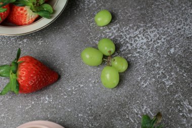 Koyu arkaplanda taze çilek ve yeşil üzüm. Tarım çiftliği. Sağlıklı beslenme tarzı.