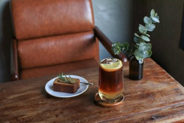 Antika kahve dükkanının ahşap masasında muzlu ekmekli Americano limon toniği. Tatlı ve yaz içeceği..