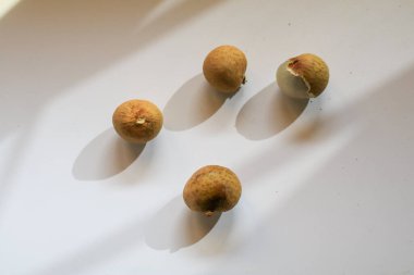 Beyaz masada güneş ışığı altında taze doğal Longan meyveleri. Dimocarpus longan. Tropik meyve.