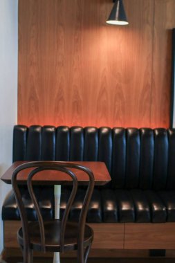 Boş ahşap masa ve kafenin rahat bir köşesinde sıcak ışığı olan sandalye. Antika tonla iç mimari.