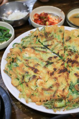 Pajeon ya da Kore Scallion Pancake 'i soya sosuyla birlikte beyaz tabakta yer. Asya yemekleri. Ev yapımı gelenek yemekleri..