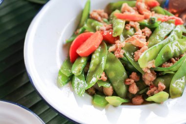 Kızarmış yeşil bezelyeleri domuz eti ve havuçla karıştırın. Ev yapımı Tayland yemeği.