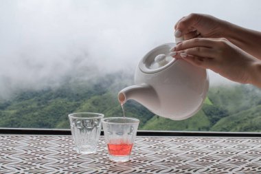 Kır evinde, dağda sis varken çaydanlıktan çayı masaya dökerek. Sağlıklı olmak için doğadan organik ürün..