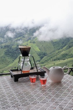 Masadaki kahve ekipmanlarını boşalt. Puslu tepeler ve dağların manzarasına bak..