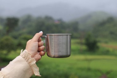 Dağ manzaralı kahve fincanı tutan kadın. Turist genç kız tatili boyunca doğanın tadını çıkarıyor..