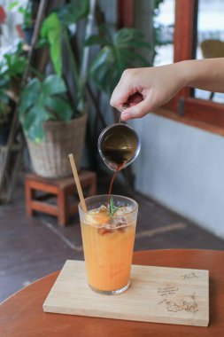 Ahşap masada portakal suyuna atılmış el yapımı espresso. Buzlu moda yaz kahvesi..
