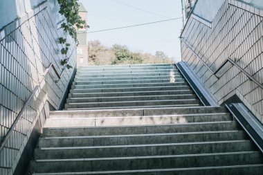 Şehir merkezindeki banyoda gün ışığında metrodan gelen tırabzanlarla beton merdivenler. Beyaz ve gri adımlar