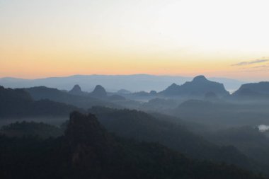 Güzel sabah dağları ve güneşin doğuşuyla sisli. Barışçıl ve atmosferik bir ortam yaratıyor. Güneş doğmadan önce.