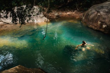 Nehirde yüzen mavi elbiseli genç kadın.
