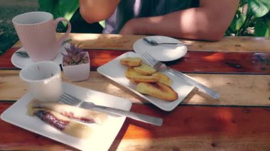Suman ve Kamote ile birlikte ahşap bir masada servis edilen samimi öğleden sonra meriendası. Kadının kahvaltı yaparken çekilmiş görüntüleri.