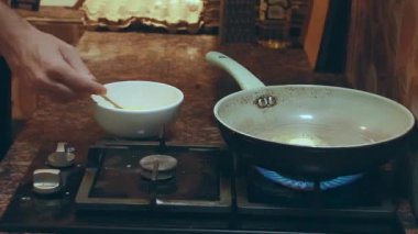 Adam yumurta çırpıyor ve tavaya döküyor. 