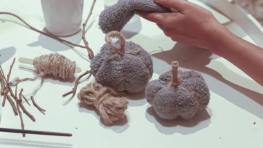 Beyaz ve sarı bir pamuk yumağıyla ağacı süsleyen bir kadının yakın plan fotoğrafı.