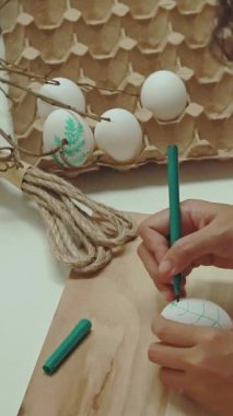 Yakın plan, kadın eli ahşap masada yumurta yapıyor. Paskalya hazırlığı.