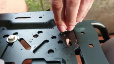 Siyah lastik eldivenli adamın eli siyah bir demir tutuyor.