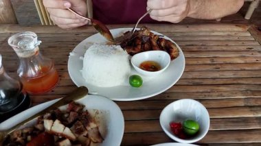 Asyalı adam kızarmış tavukla pilav yiyor.