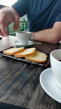 Bir adam bir fincan kahveyle tost yiyor..