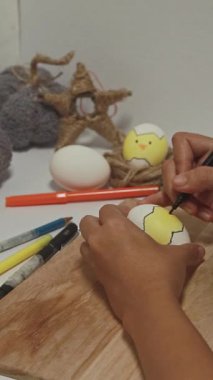 Bir çocuk paskalya yumurtalarını çizer.