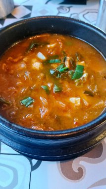 Siyah kasede kaynayan baharatlı tofu güveci.