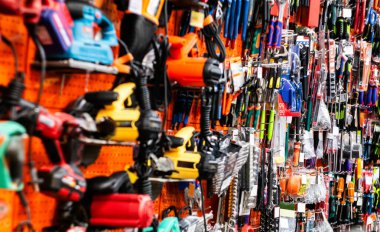 Tahtada çeşitli el ve elektrikli aletleri gösteren bir alet deposu duvarının geniş görünümü. Nalbur dükkanında parlak turuncu bir tahtanın üzerinde çeşitli güç ve el aletlerini gösteren ayrıntılı resim.