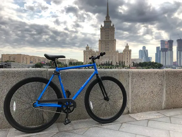 Dişlisiz mavi modern bir bisiklet, ormanda eski bir ağaca yaslanmış bir gölün yanında duruyor. Yüksek kalite fotoğraf