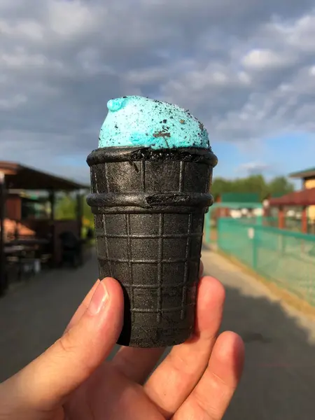 Yaz tatilinde bulanık bir şehrin arka planına sahip siyah bir külahta dondurma. Yüksek kalite fotoğraf