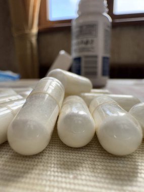 Beyaz baş ağrısı hapı kapsül ve ilaç kavanozlarındaki diğer beyaz hapların arka planına yakın çekim yap. Yüksek kalite fotoğraf