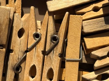 Çamaşır iğneleri bej renkli ahşap ve plastik renkli mandallar yakın mesafeden alınmış güneş ışınlarının altında gümüş metal yaylarla birlikte duruyor. Yüksek kalite fotoğraf