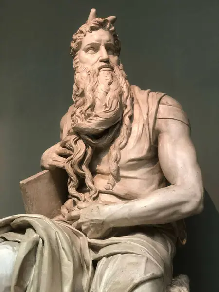 Uzun sakallı ve elinde bir kitapla yeşil arka planda bir bankta oturan bir adamın heykeli. Yüksek kalite fotoğraf