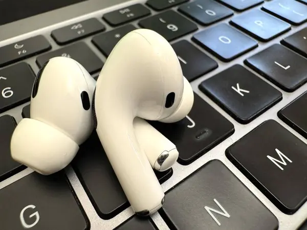 Laptopta duran kablosuz beyaz kulaklıklar, yakın mesafeden çekilmiş. Yüksek kalite fotoğraf