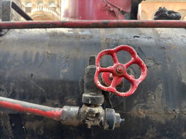 Siyah arka planda metalden yapılmış kırmızı kapakçık ve sağ tarafta kırmızı gaz borusu. Yüksek kalite fotoğraf