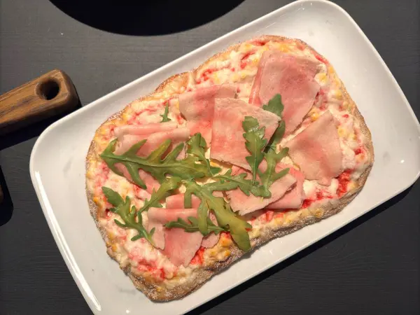 Beyaz tabakta jambonlu kare pizza ve gri masa. Yüksek kalite fotoğraf