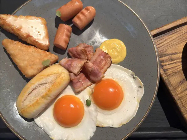 Gri bir tabak yumurta, pastırma, ekmek, sosis ve tost. Yüksek kalite fotoğraf