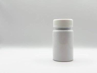 Kapağı kapalı beyaz ilaç kavanozu soldaki beyaz arka planda duruyor. Yüksek kalite fotoğraf