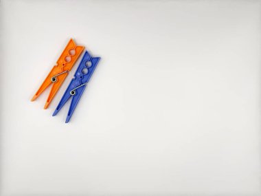 Plastik mandallar, üstten bakıldığında solda beyaz bir zemin üzerinde mavi ve turuncu renkli metal yaylarla çok renkli. Yüksek kalite fotoğraf