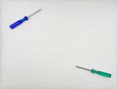 Plastik saplı iki renkli tornavida, beyaz arka plan manzaralı mavi yeşil sol alt ve sağ üstte. Yüksek kalite fotoğraf