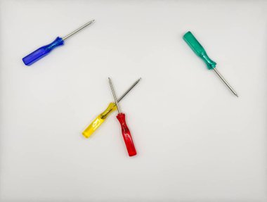 Plastik saplı dört renkli tornavida ortada mavi, yeşil, beyaz arka plan manzaralı. Yüksek kalite fotoğraf
