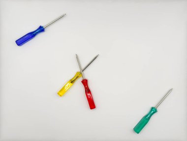 Plastik saplı dört renkli tornavida mavi, yeşil, sol üstte, sağ altta ve ortada beyaz arka plan manzaralı. Yüksek kalite fotoğraf