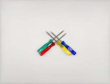 Plastik saplı dört renkli tornavida ortada mavi, yeşil, beyaz arka plan manzaralı. Yüksek kalite fotoğraf