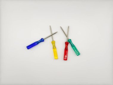 Plastik saplı dört renkli tornavida ortada mavi, yeşil, beyaz arka plan manzaralı. Yüksek kalite fotoğraf