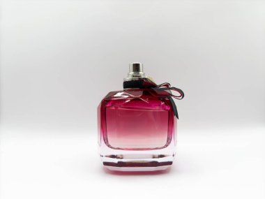 Mor renkli cam bir parfüm şişesi. Görüntünün tam ortasında beyaz bir arka planda fiyonk var. Yüksek kalite fotoğraf