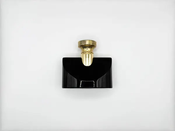 Beyaz arka planda altın dikdörtgen kapaklı siyah parfüm şişesi. Yüksek kalite fotoğraf