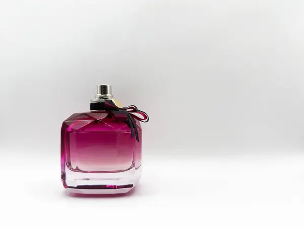 Cam bir parfüm şişesi mor renkli, kapağında beyaz arka planda bir fiyonk var. Yüksek kalite fotoğraf